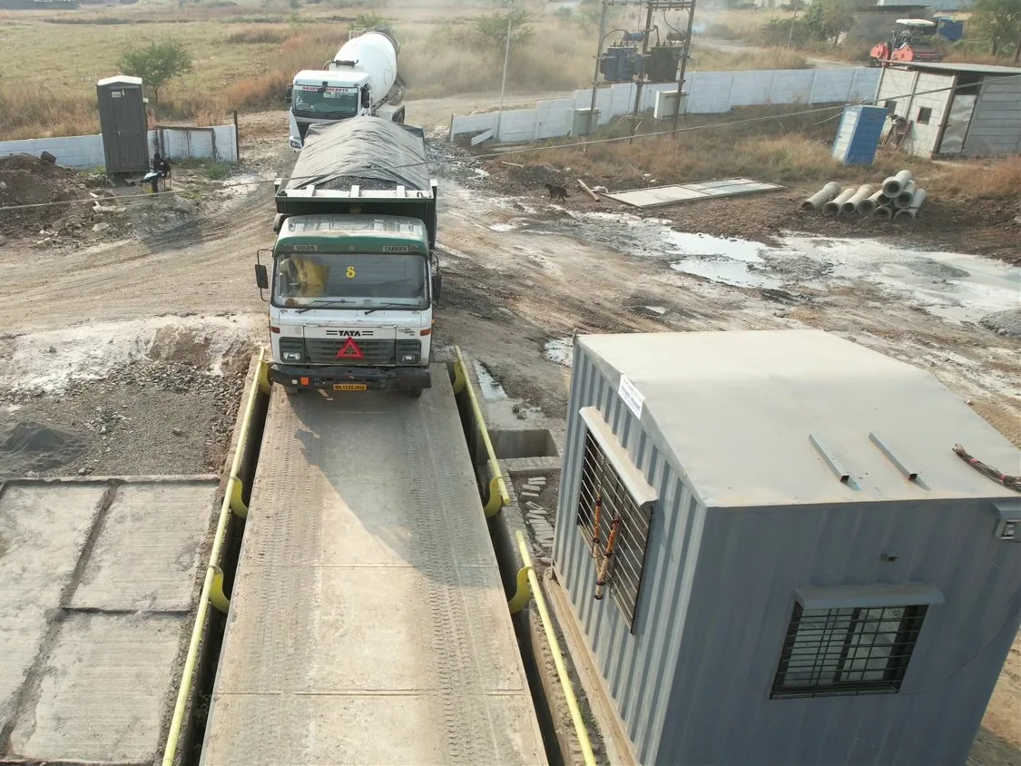 A truck crossing the weighbridge at the plant gate, with the weighbridge cabin